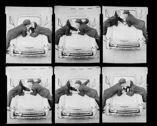 NP_NP05E4_1957_026A: Couple lighting cigarettes over a car, Vogue BW 1957