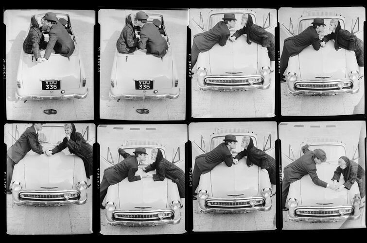 NP_NP05E4_1957_026B: Couple lighting cigarettes over a car, Vogue BW 1957